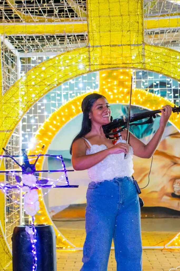 A violinist playing beneath a lit arch in San Nicolas