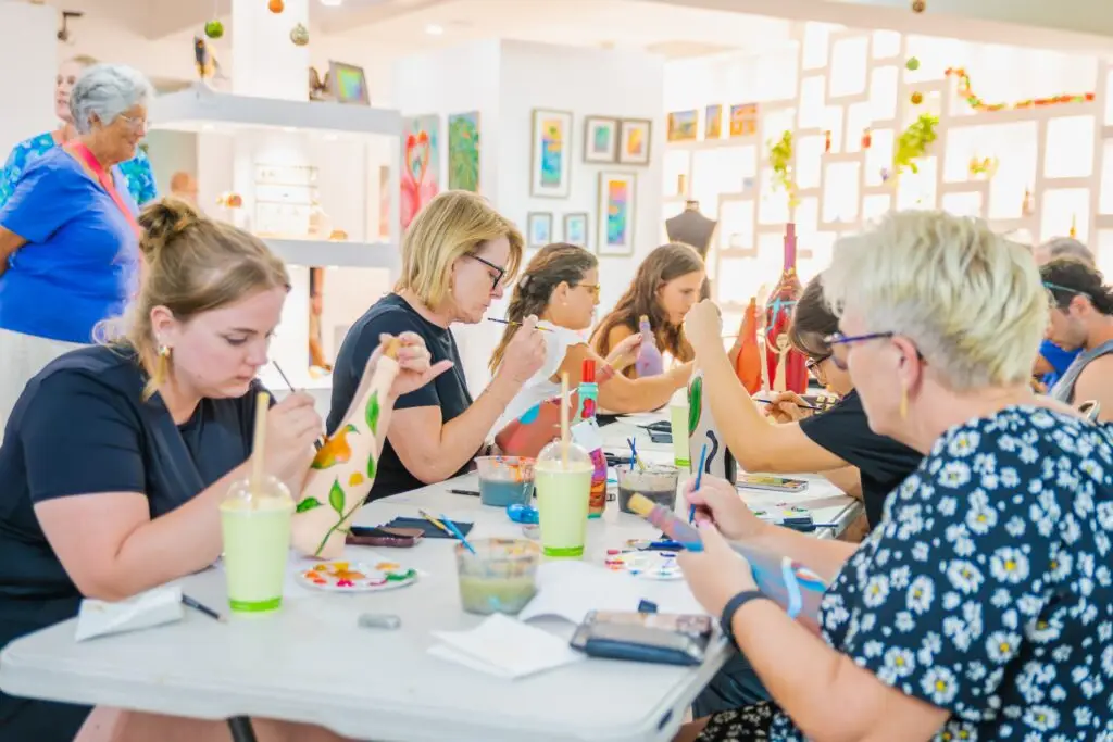Participants painting at the long workshop table inside ArtisA